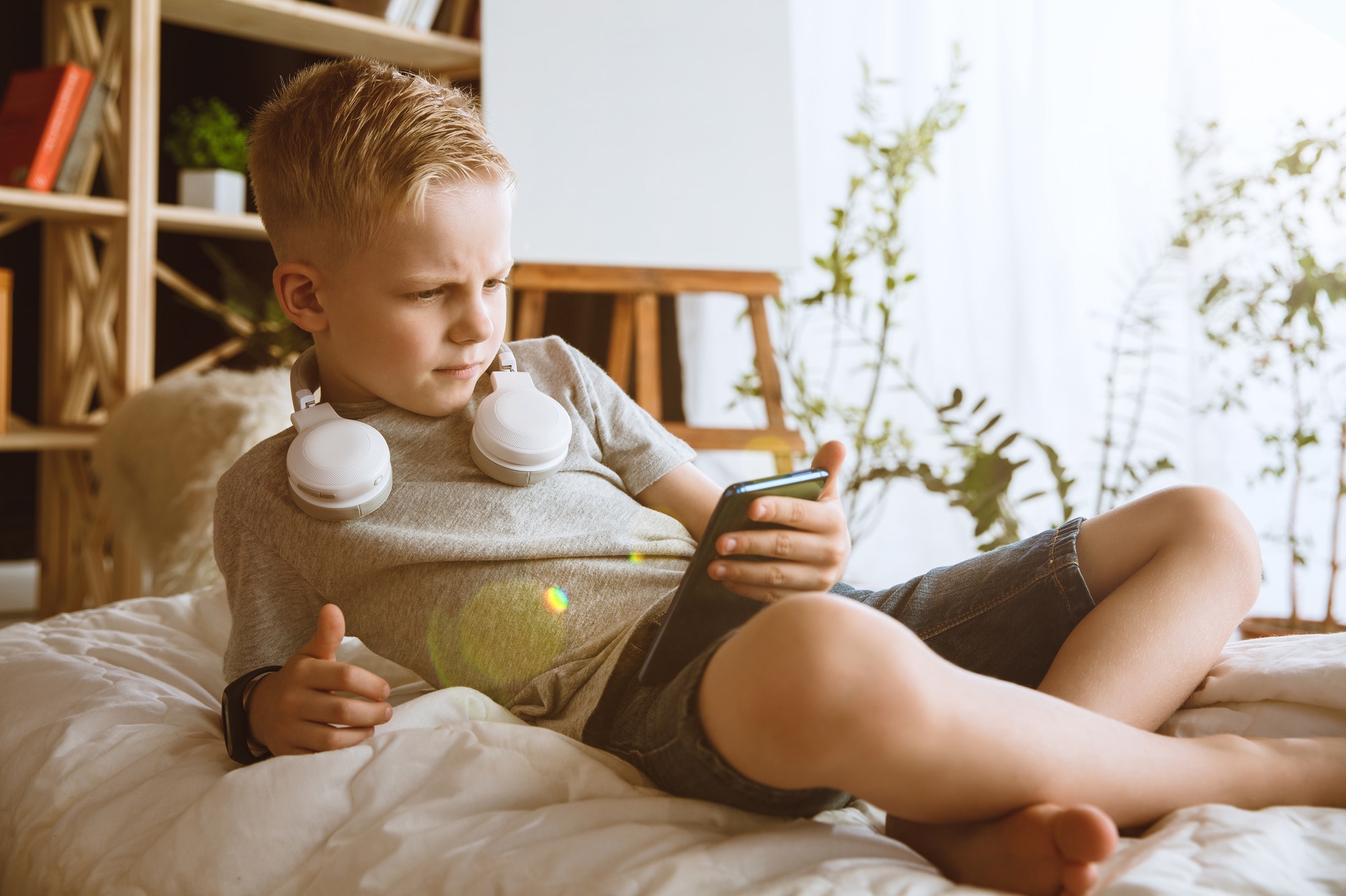 Little boy using different gadgets at home