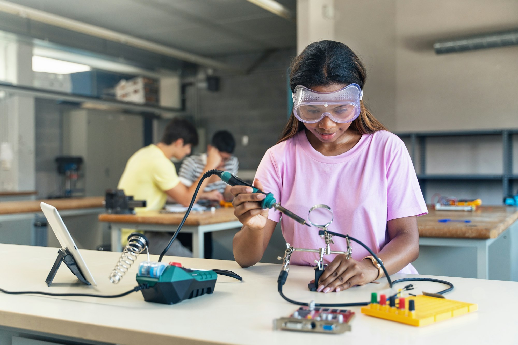 African American High School teenage Studentsoldering electronics circuit in technology workshop