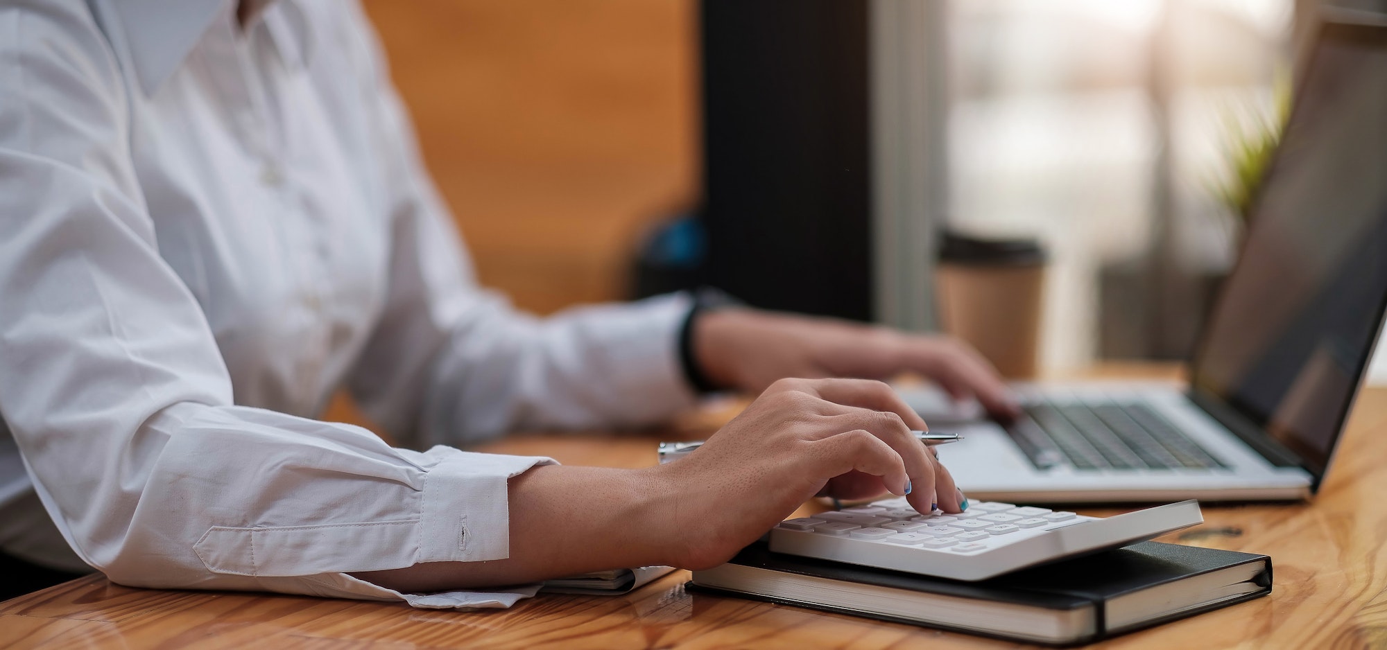 Close up Business woman using calculator and laptop for do math finance on wooden desk in office and